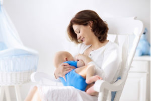 Mãe amamentando em um quarto para bebê com móveis planejados